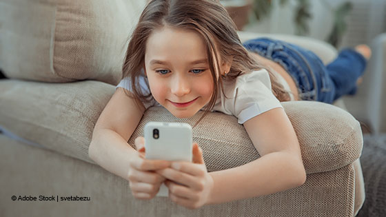 kind mit handy auf couch